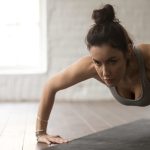 Young attractive woman in chaturanga dandasana pose, white loft