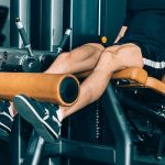 Muscular man exercising in gym, leg extension machine workout