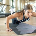 Young sporty woman doing Knee push-ups on exercise mat at gym.