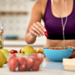Close-up of female athlete making fruit salad in the kitchen.