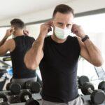 homem-colocando-mascara-medica-na-academia