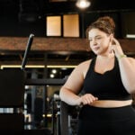 A young plus-size woman engages in her workout routine, embracing body positivity at the gym.