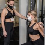 mulher-jovem-se-exercitando-na-academia-e-seu-personal-trainer
