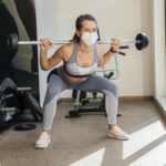 mulher-se-exercitando-na-academia-com-equipamentos-e-mascara-medica