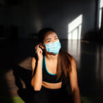 Portrait of fit woman putting on a protective face mask.