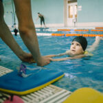 Girl learning to swim with coach at the leisure center