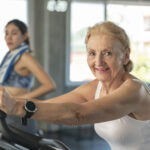 Senior woman exercising spinning bike in fitness gym. elderly he