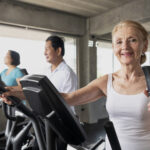 Senior woman exercising spinning bike in fitness gym. elderly he